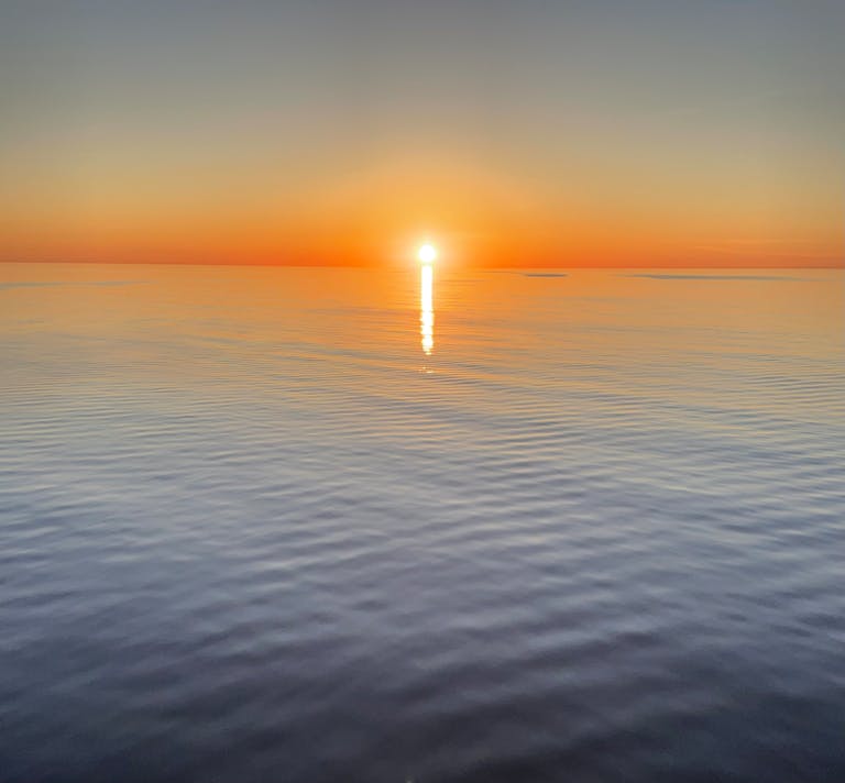 A breathtaking view of the sunset casting vivid colors over a tranquil sea.
