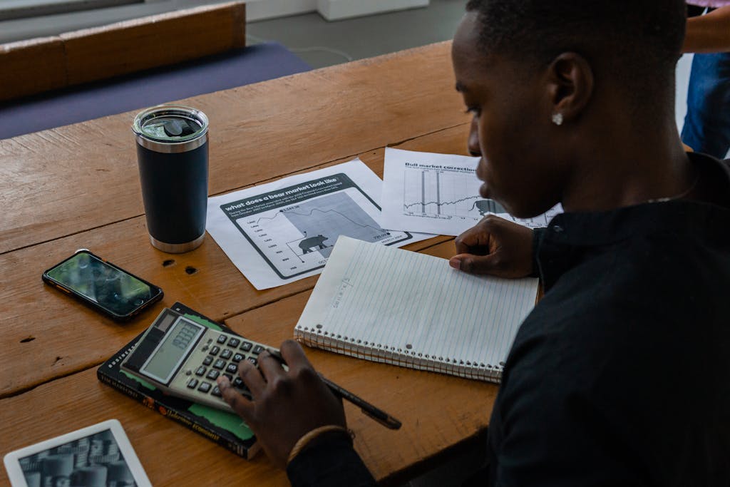 Young professional evaluating financial data using a calculator and notes.
smart financial habits and money mindset